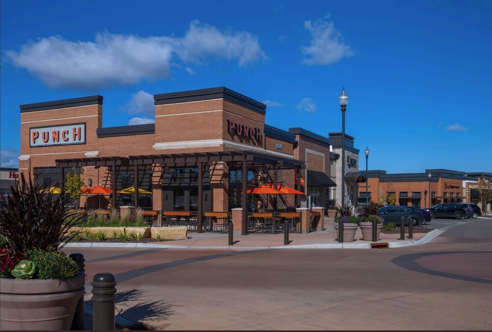 Brick retail center with a restaurant patio and orange umbrellas