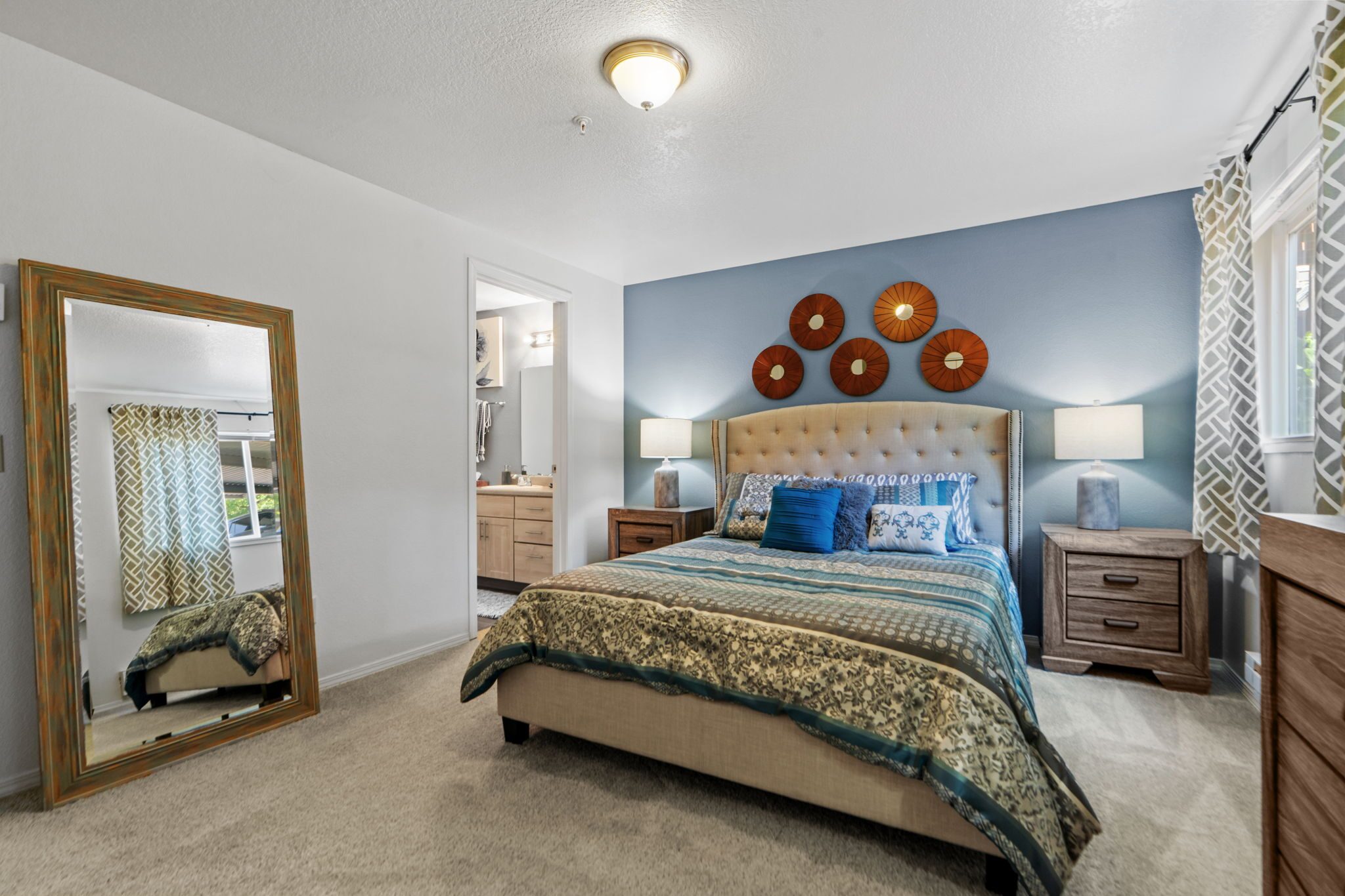 Bedroom with a tufted headboard and blue accent wall at Creekside Apartments