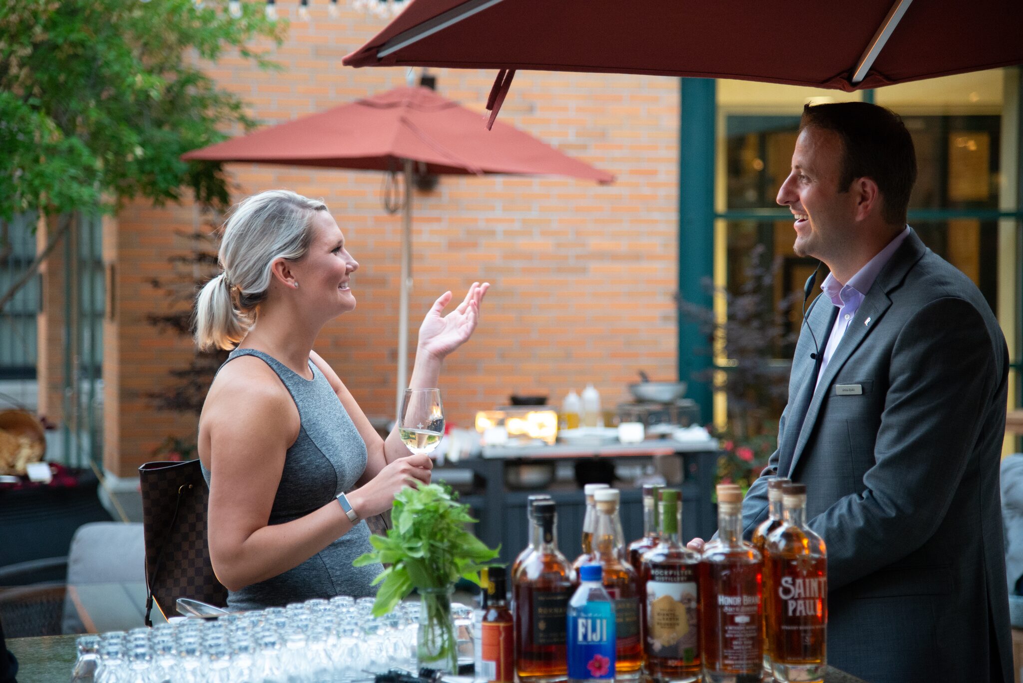 Hotel staff member chatting with a smiling guest at an outdoor patio bar